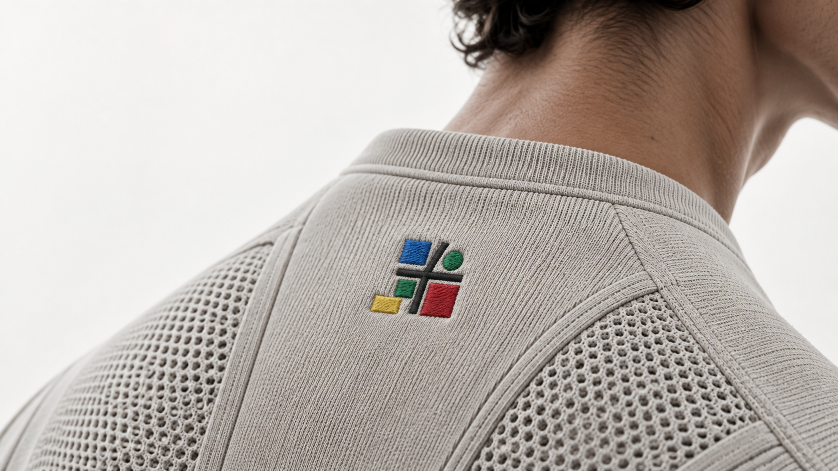 Close-up of the embroidered KUBIA logo on the back collar of a knit sweatshirt.